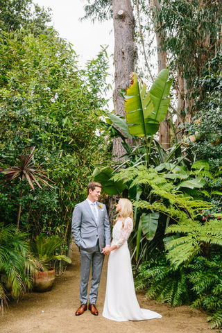 a bride and groom are holding hands around lush green trees 