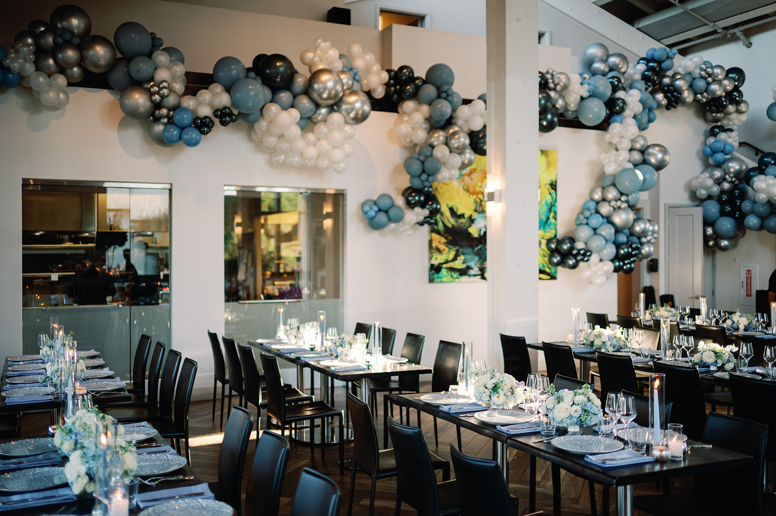 Long dinner tables under blue and silver balloon garlands