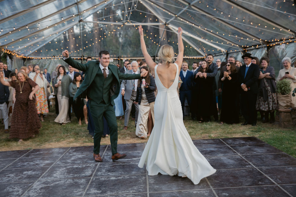a bride and groom are dancing in a clear tent