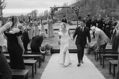 a black and white photo of a bride and groom walking down the aisle