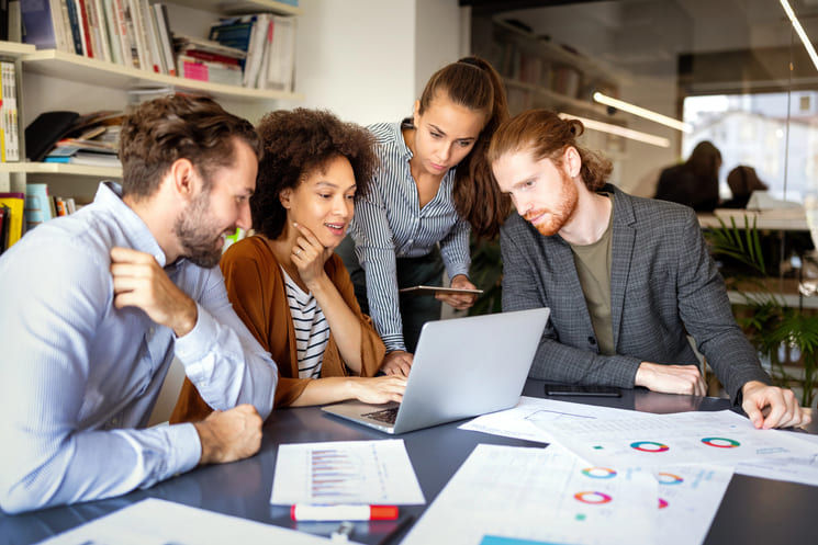 People huddled over a laptop strategizing about a capital campaign