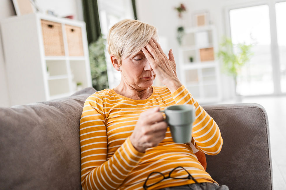 Woman with headache, hand to forehead, holding mug