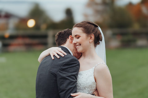 Bride and groom embracing in a rustic barn wedding setting.