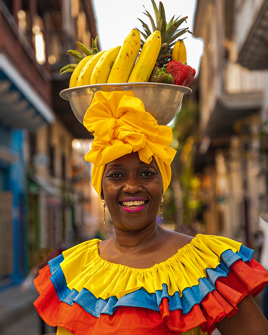 Palenquera woman in colorful traditional dress carrying fruit in Cartagena’s historic streets.