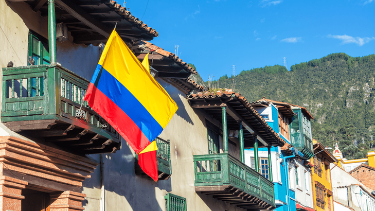 Historic street in La Candelaria, Bogotá with a Colombian flag and colonial architecture.