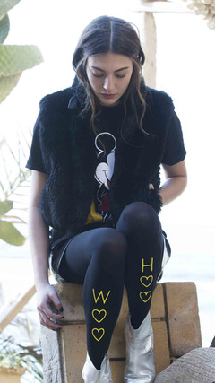 Lady sitting wearing thick tights with the words Woo Hoo written vertically down the Zohara tights.