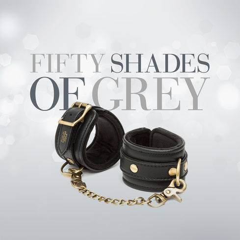 Fifty Shades logo behind set of black leather wrist cuffs.