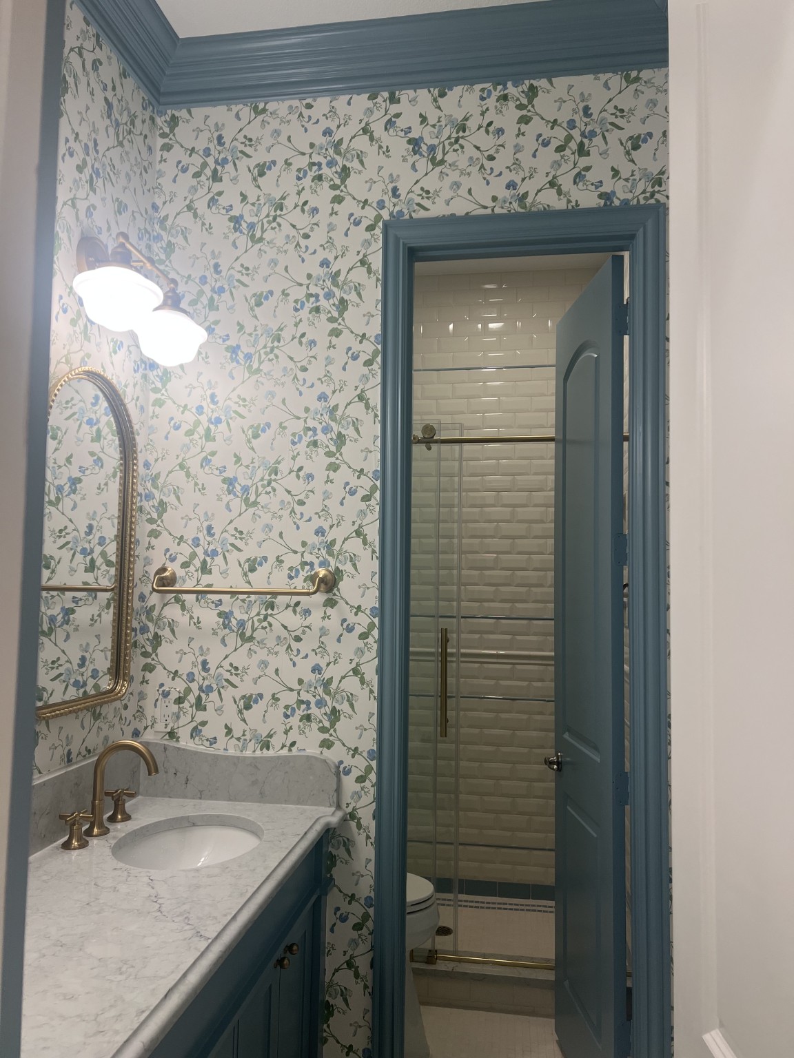 Blue Floral Bathroom. Delicate blue botanicals paired with painted blue trim and warm brass fixtures.