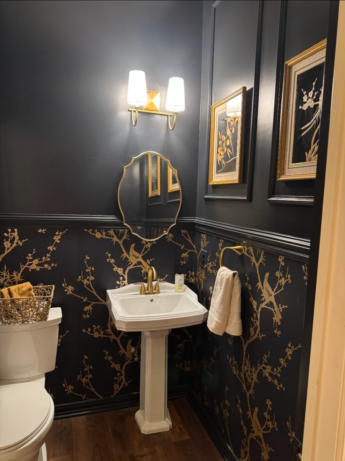 The Moody Powder Bath. Statement powder bathroom with charcoal walls, brass botanical wallpaper, gold fixtures and dramatic trim.