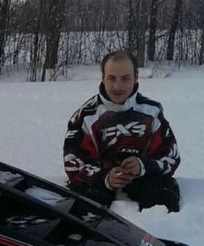 Michael Brandwood sitting in the snow smilig
