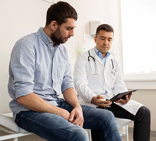 Man sitting with a doctor in a doctor's office reviewing a medical chart. 