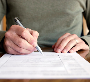 Man holding a pen about to sign a document. 