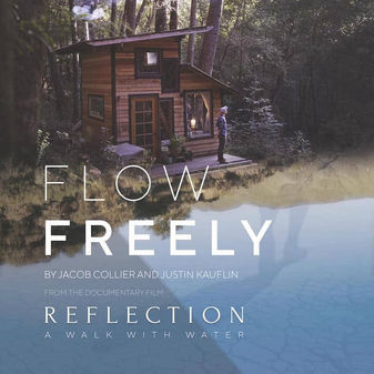 Cabin with man standing outside by a stream