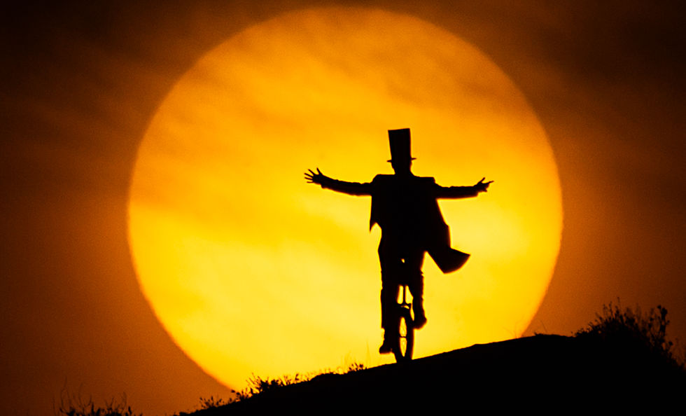 Silueta hombre monociclo, puesta sol