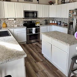Cocina limpia con gabinetes blancos y encimeras de granito.