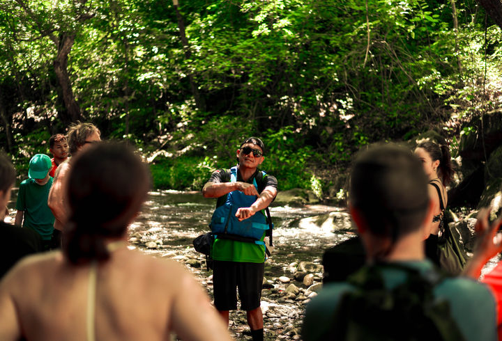 Tour guide explaining La Leona Waterfall features to visitors in Costa Rica.