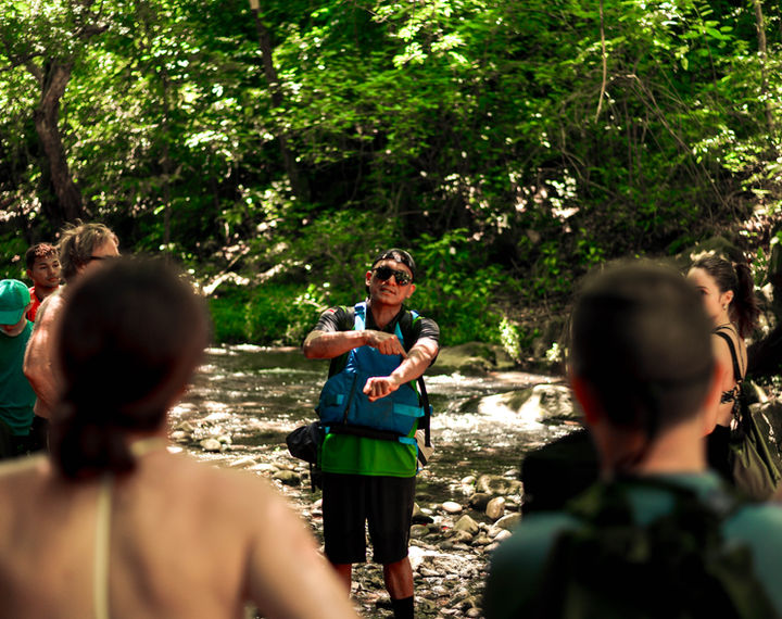 Tour guide explaining La Leona Waterfall features to visitors in Costa Rica.