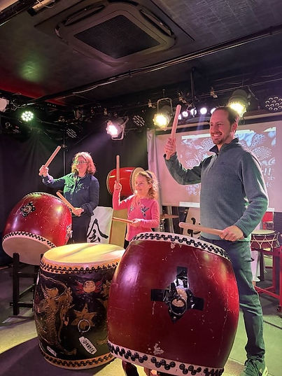 Parents and child playing taiko drums together during a family-friendly taiko workshop in Kyoto Japan