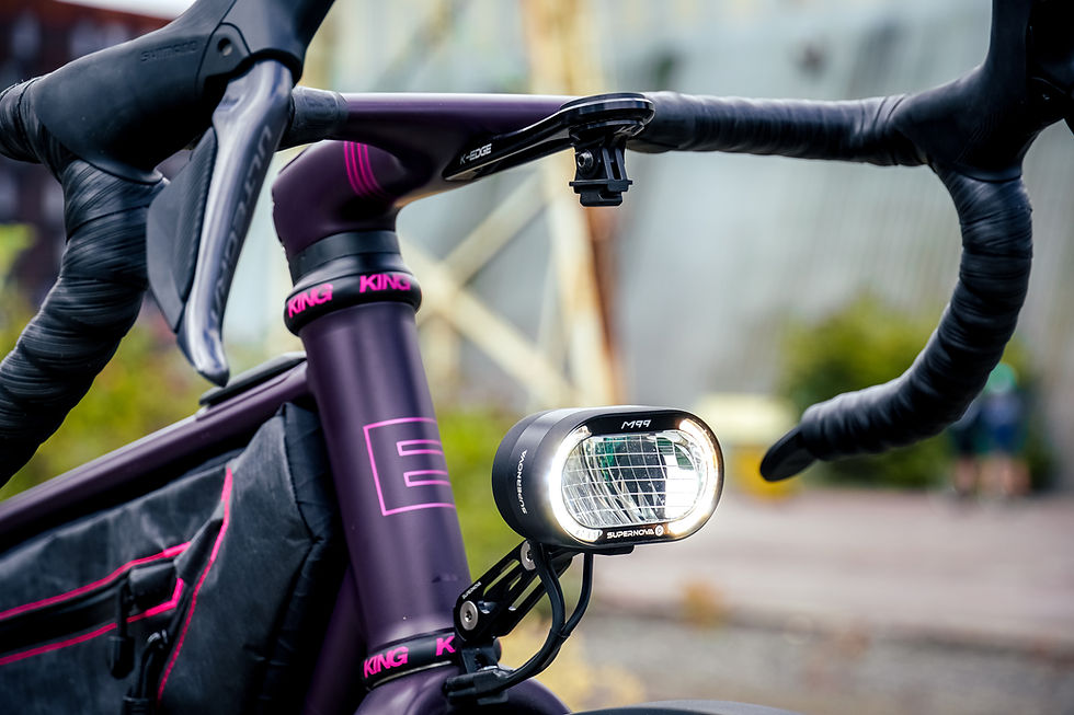 Close-up of a front light mounted on the handlebars of a purple gravel bike