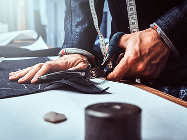 fashion-designer-is-cutting-off-fabric-with-scissors-he-is-wearing-denim-closeup-photo-sho