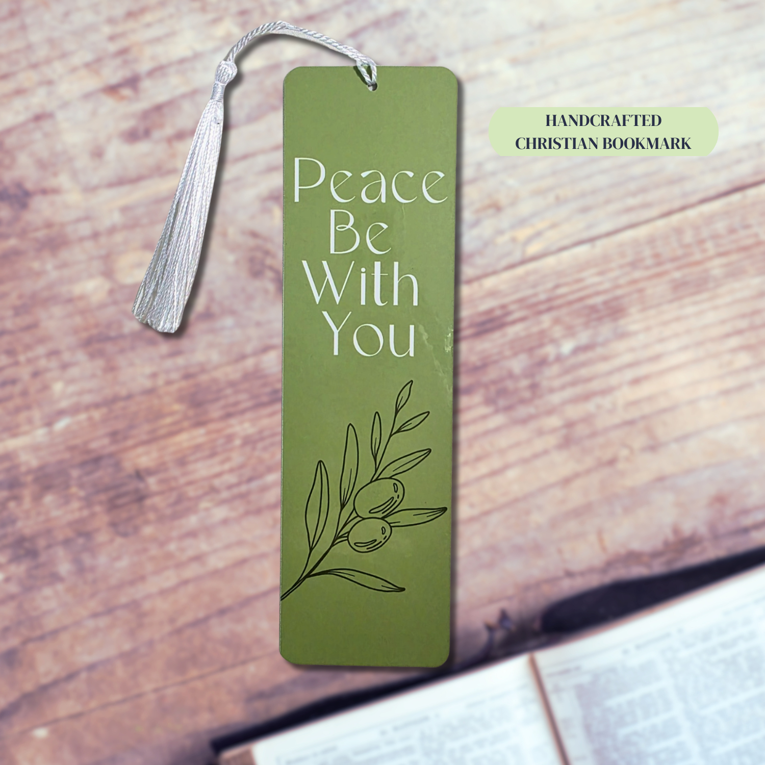 “Handcrafted Peace Be With You green bookmark with tassel on rustic wood surface.”