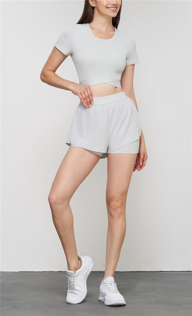 Woman wearing the light grey BareFeel Cross-Hem Yoga Tee with matching shorts and white shoes.