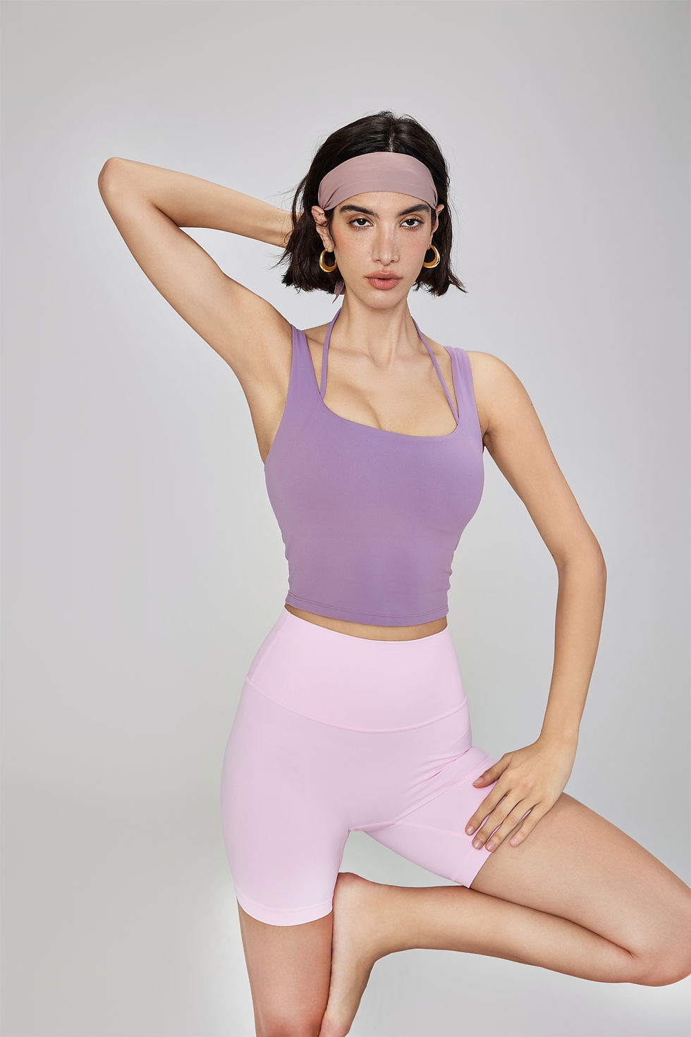 الصورة المصغرة: Woman wearing the SleekFusion Halter Sports Bra in purple with light pink biker shorts.
