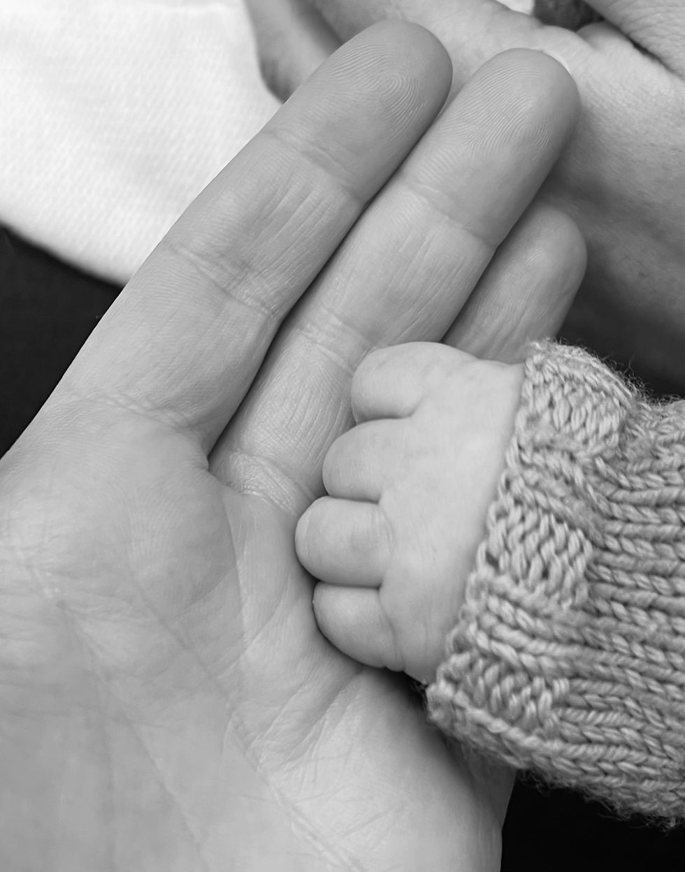 Black and white photo of a baby's hand in an adult's hand