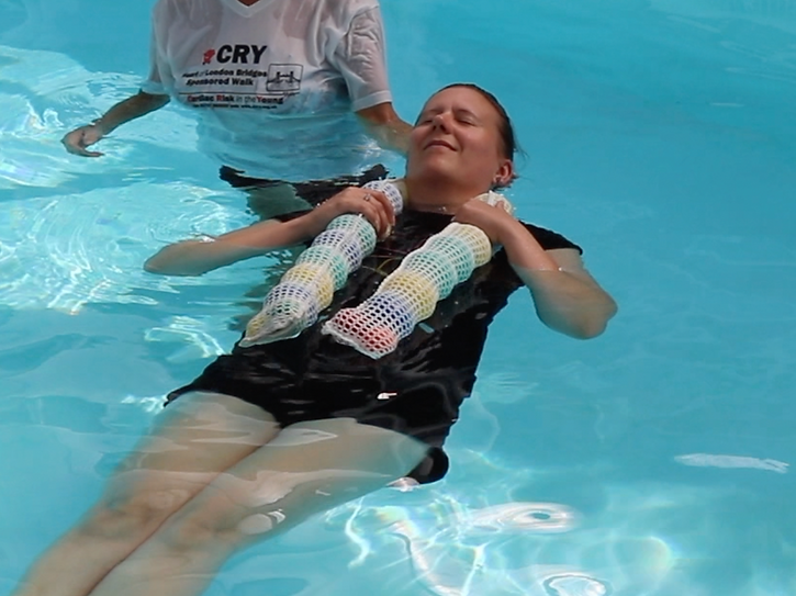 A student and an instructor in a pool. The student has the Sensatube device around her neck as a floatation device