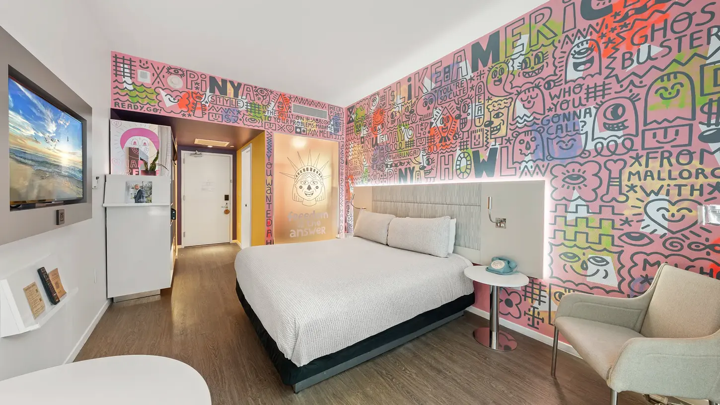 Stylish hotel guest room with modern decor, vibrant accent wall, and premium furnishings photographed for hotel marketing.