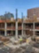 Mid-rise building under construction with exposed concrete structure and workers on site, construction photography NYC development project