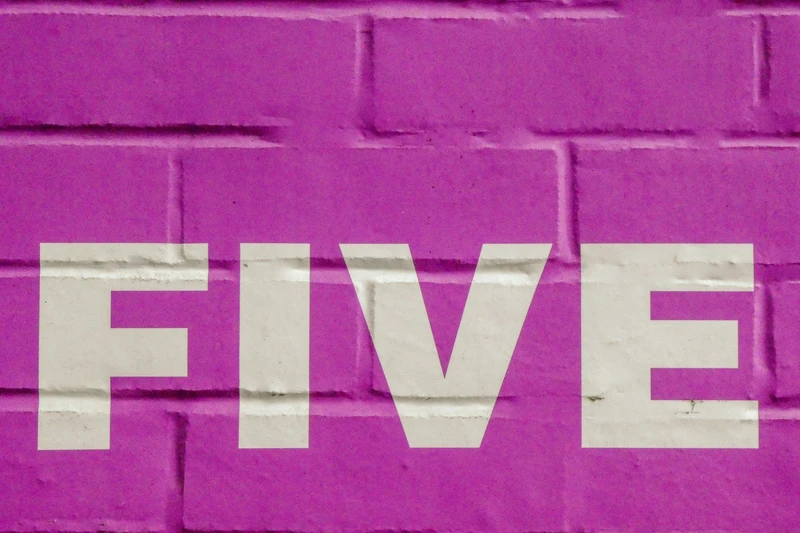 Schriftzug "Five" auf rosa Mauer