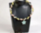 Pastel beaded necklace with flower pendant displayed on a black jewelry stand
