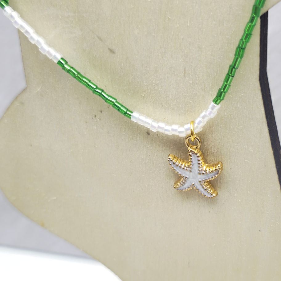 Handcrafted green and white beaded anklet with an off-white starfish charm displayed on a foot form