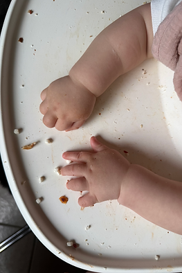 Baby exploring finger foods on a highchair tray while developing self-feeding skills during the transition to solid foods.