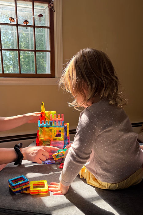 Pediatric speech therapist using play-based activities to build communication and language skills with a young child during an in-home therapy session.