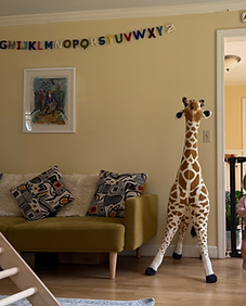Bright home-based pediatric speech therapy playroom featuring a cozy reading nook, alphabet banner, and plush giraffe for child-led learning.