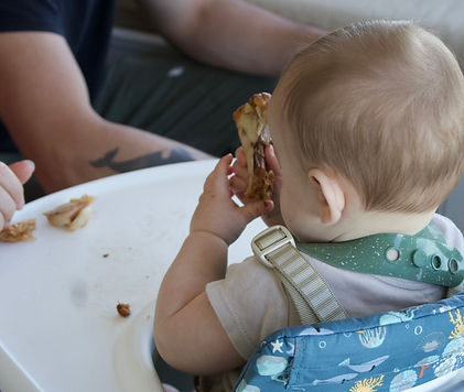 Baby practicing self-feeding during a baby-led weaning session with hands-on starting solids support.