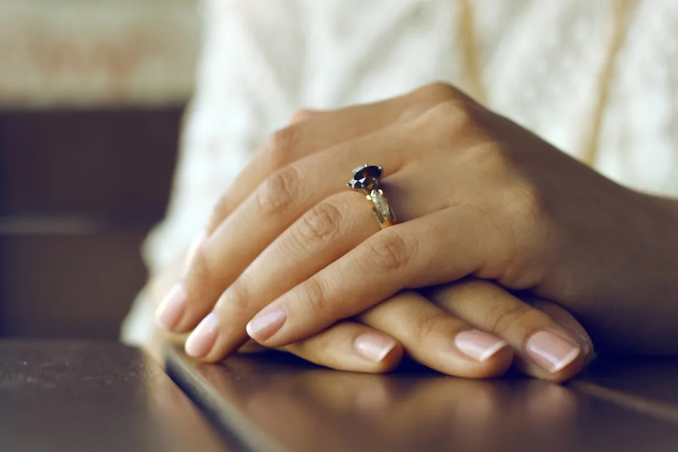 Close-up of neatly manicured hands with a classic nude polish and elegant gemstone ring – perfect finish from a nail salon near me.