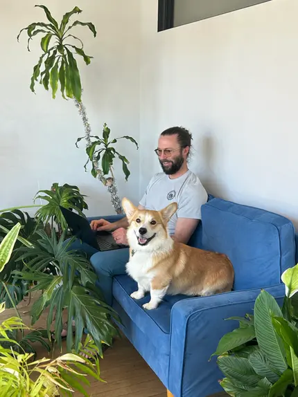 Member working on the sofa with his dog.