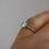 Thumbnail: Close up view of model wearing diamond solitaire ring.