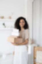 Mixed-race woman holding white and brown flat-rate shipping boxes.