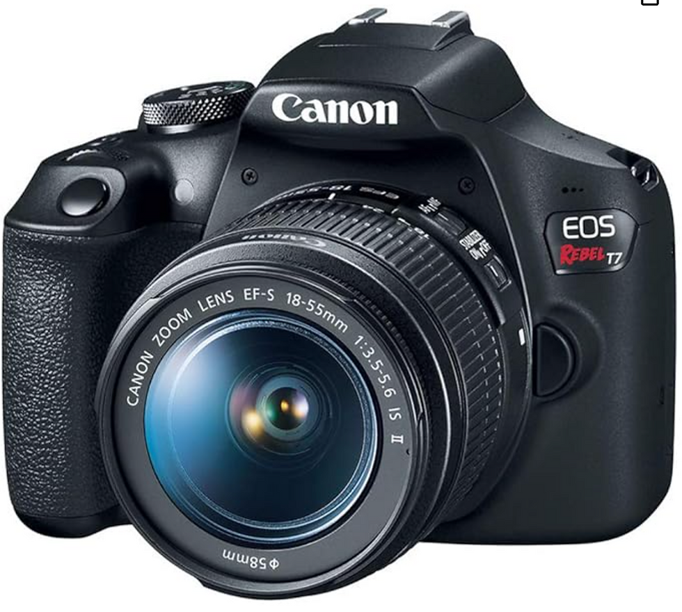 Black Canon EOS Rebel T7 camera with 18-55mm lens. Text on camera reads "Canon" and "EOS Rebel T7." Close-up on white background.