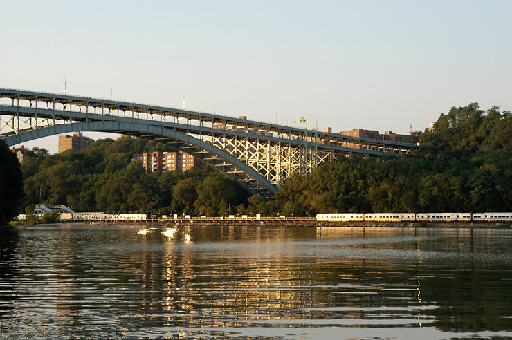 Scenic photo capturing the waterfront vista with a subway train passing by and the iconic George Washington Bridge in the background.