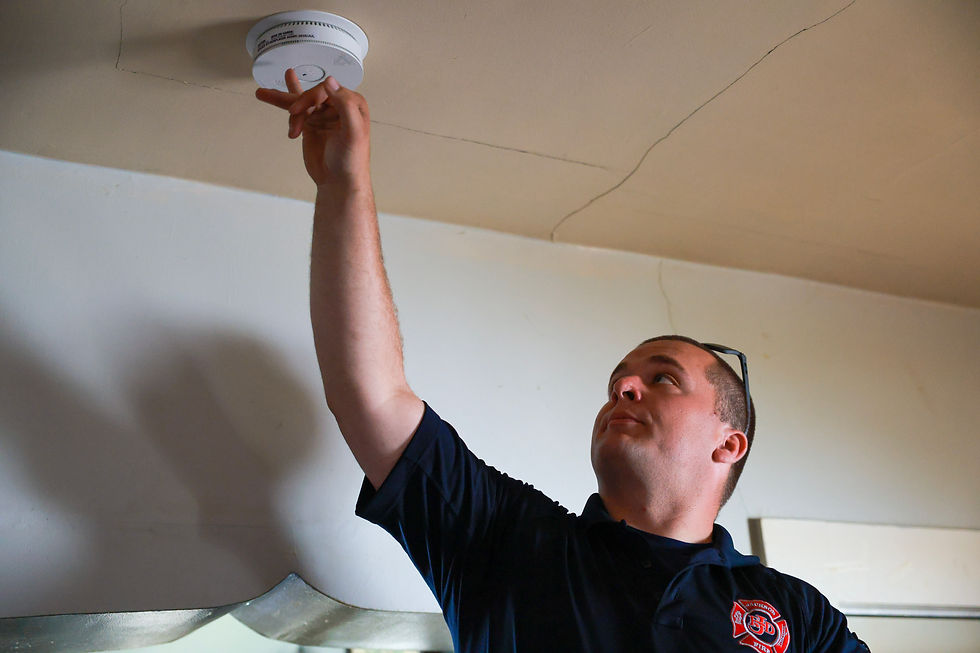 A man installs a carbon monoxide alarm on the ceiling. 