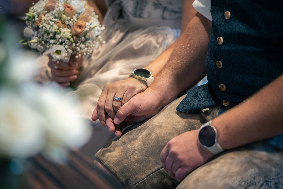 a bride and groom hold hands with the bride wearing a wedding ring
