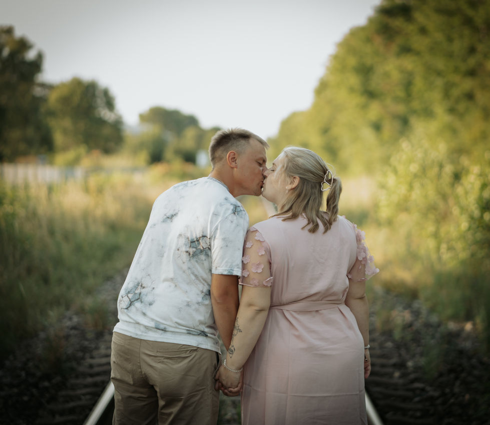 a man in a tie dye shirt kisses a woman in a pink dress