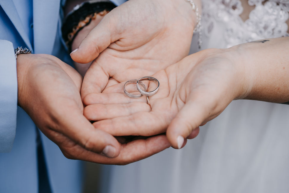 a bride and groom hold their wedding rings in their hands