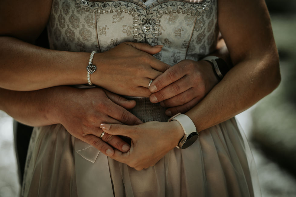 a woman wearing a heart shaped bracelet is holding a man 's hand