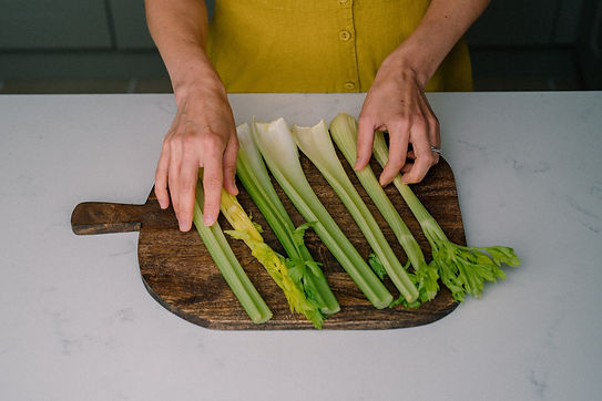 Photo of separated celery ribs on a wooden chopping board with Ksenias hands separating them.jpg